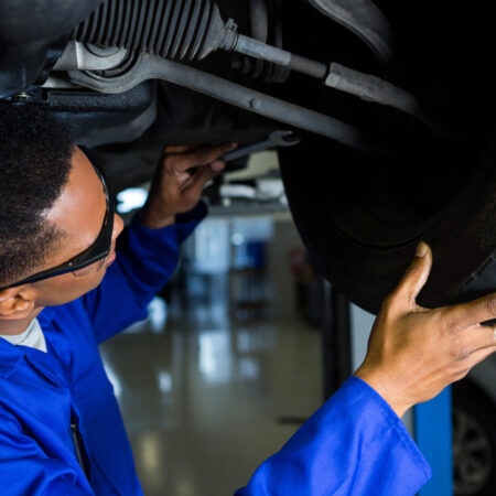 Attentive mechanic examining car tyre at repair garage